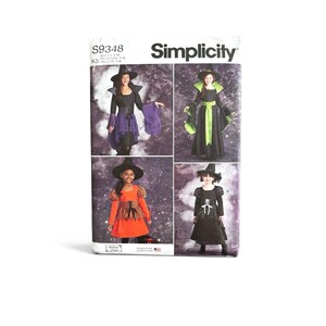 May include: Simplicity sewing pattern S9348 featuring four witch costume variations. The designs include black and purple, black and green, orange and black, and black and white outfits, all paired with pointed hats for sizes 7-14.