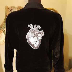 May include: A black velvet jacket with a detailed anatomical heart embroidered on the back.