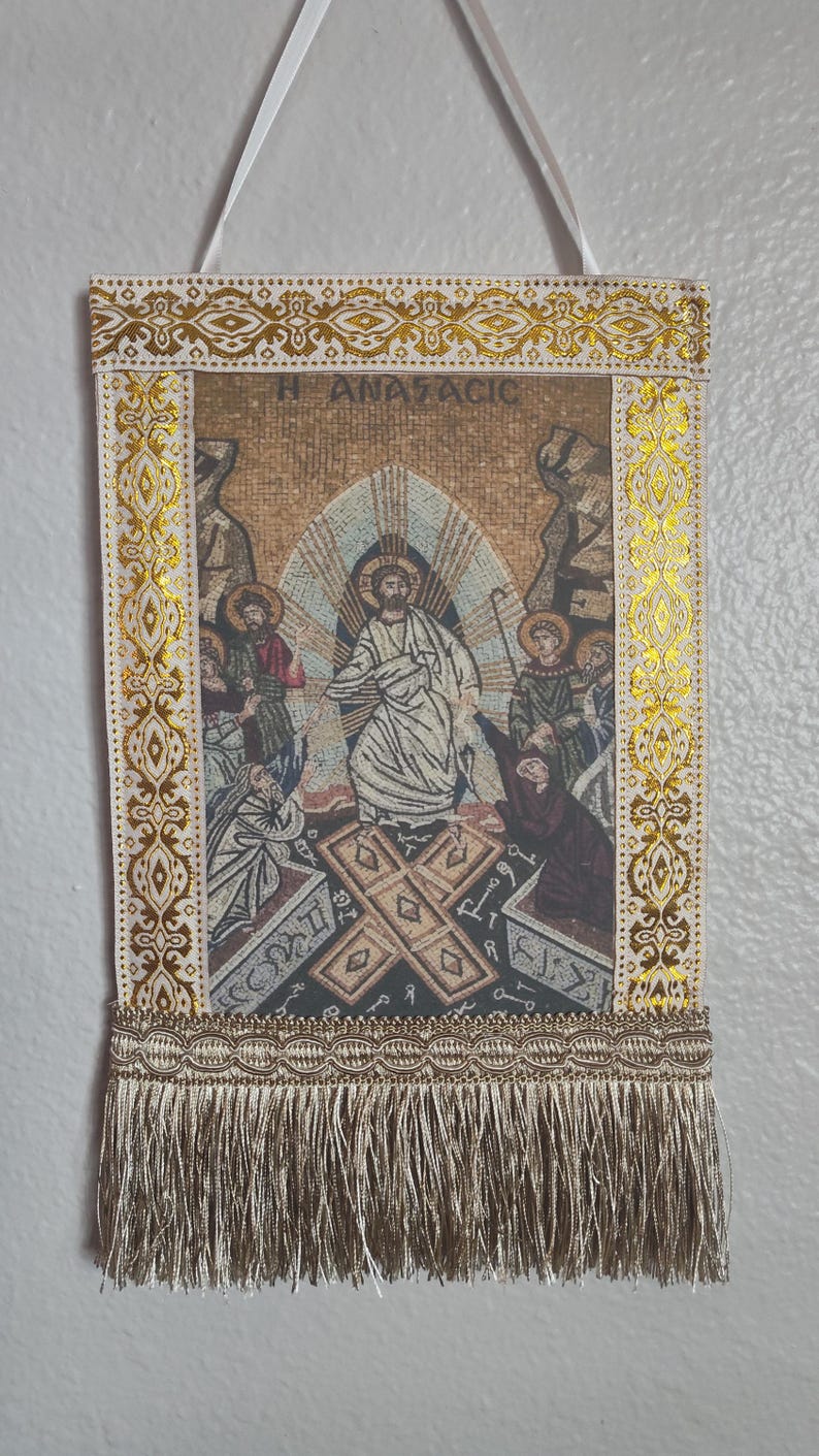May include: Rectangular tapestry with a religious mosaic scene, featuring figures in robes and halos. The tapestry has gold trim, a decorative border, and a fringe at the bottom. The text "H ANASTACIC" is visible at the top.