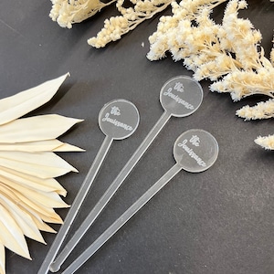 May include: Three clear acrylic cocktail stirrers with round, engraved tops that say "The Jouissance".
