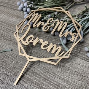 May include: Gold geometric cake topper with the text "Mr & Mrs [Last Name]" in a cursive font.