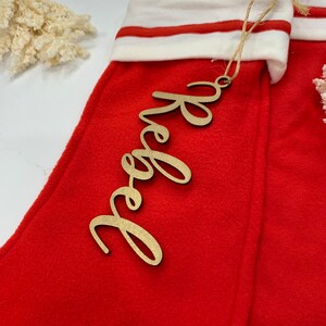 May include: A red stocking with a white cuff and a wooden tag that says "Hope" in gold lettering.