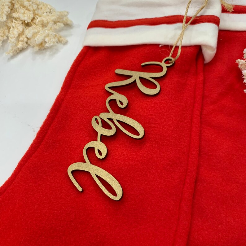 May include: A red stocking with a white cuff and a wooden tag that says "Hope" in gold lettering.