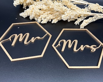 May include: Two gold hexagonal wooden signs with the words "Mr." and "Mrs." in cursive script.