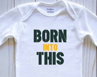 May include: White long-sleeve baby onesie with the text "BORN INTO THIS" in green and yellow letters.