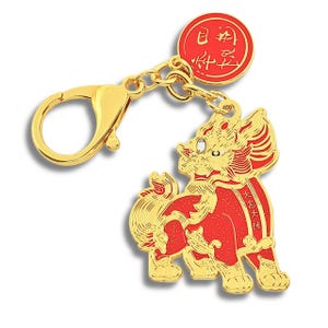 May include: A gold-colored charm with a red and gold mythical creature design. The charm is attached to a gold chain and clasp. A red circular pendant with gold text is also attached to the chain.