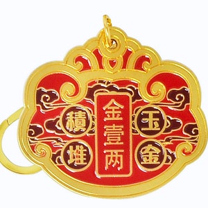 May include: Gold-colored metal keychain with a red and black design. The keychain features Chinese characters that read "Golden Fortune Two" and "King Gold".