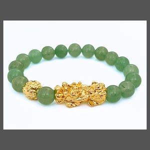 May include: A green jade stone bracelet with a gold dragon charm. The bracelet is made of round beads and has a stretchy band.