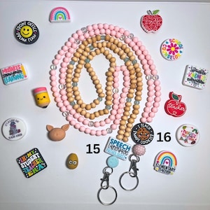 May include: Two lanyards made of pink silicone and natural wood beads, each featuring a metal clasp and a key ring. One lanyard has a rectangular tag reading Speech Language Pathologist, the other a round tag reading I Teach Smart Cookies.