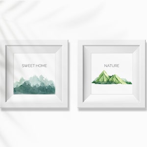 Puede incluir: Dos impresiones enmarcadas blancas con ilustraciones de acuarela de monta&ntilde;as. La impresi&oacute;n de la izquierda dice "SWEET HOME" y la impresi&oacute;n de la derecha dice "NATURE".