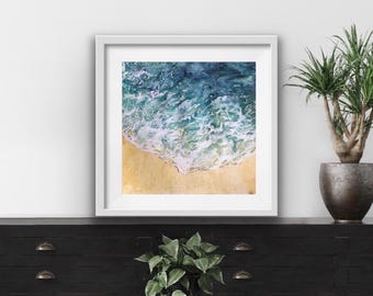 May include: A framed watercolor painting of a beach scene with blue and green water crashing onto a sandy shore.