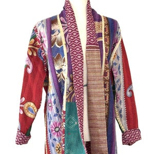 May include: A patchwork jacket with a variety of patterns and colors, including red, purple, blue, and green. The jacket is displayed on a mannequin and features floral and geometric designs.