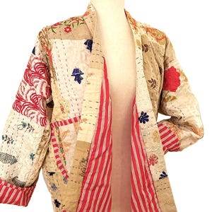 May include: A patchwork jacket with a beige base, featuring red and white striped lining and accents. The jacket is adorned with floral and geometric patterns in red, blue, and beige, showcasing a quilted design.