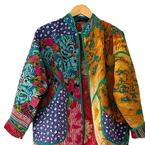 May include: A colorful patchwork jacket with a teal green trim. The jacket has a mandarin collar and a front zipper closure. The fabric is a mix of floral and geometric patterns.