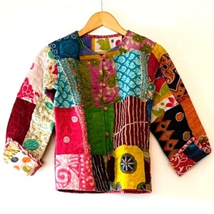 May include: A patchwork jacket with a variety of colorful fabric squares. The jacket has long sleeves and a button-up front. The fabric squares feature floral, geometric, and abstract patterns in shades of pink, blue, green, and yellow.
