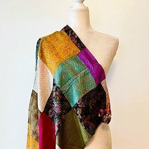 May include: A colorful patchwork scarf with a variety of colors and patterns, including yellow, green, purple, red, and brown. The scarf is draped over a mannequin.