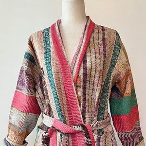 May include: A striped, multi-colored robe with a pink sash. The robe is made of a soft, woven fabric and has a relaxed fit.