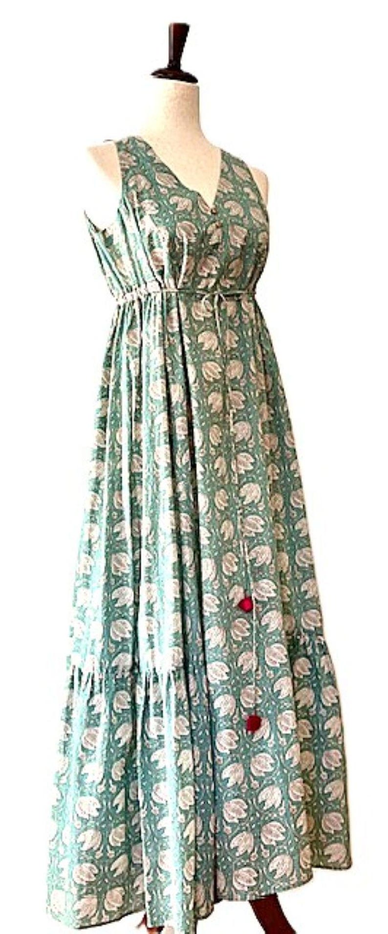 Puede incluir: Un vestido maxi sin mangas con escote en V y estampado floral. El vestido tiene una cintura ajustada y una falda de capas. El vestido est&aacute; hecho de una tela ligera y es perfecto para el clima c&aacute;lido.