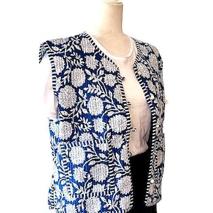 May include: A blue and white quilted vest with a floral pattern. The vest has a button closure and a sleeveless design.