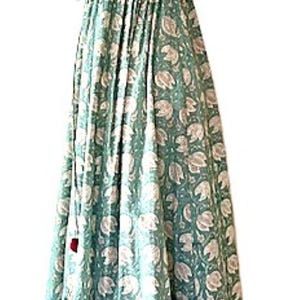 Puede incluir: Un vestido maxi largo y fluido de color verde con estampado floral blanco. El vestido tiene un escote halter y un lazo en la cintura.