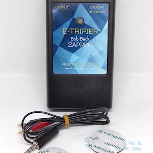 May include: Black electronic device labeled "E-TRIFIER Bob Beck ZAPPER" with a dial and output port. Includes a cable with red and black connectors, and two round electrode pads. The device has the text "Fractal Solution" and a website address.