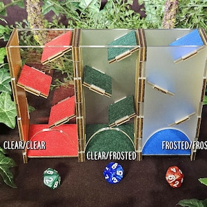 May include: Three clear acrylic dice towers with different frosted glass panels. The towers are labeled "CLEAR/CLEAR", "CLEAR/FROSTED", and "FROSTED/FROSTED".  Each tower has a different colored felt base: red, green, and blue.