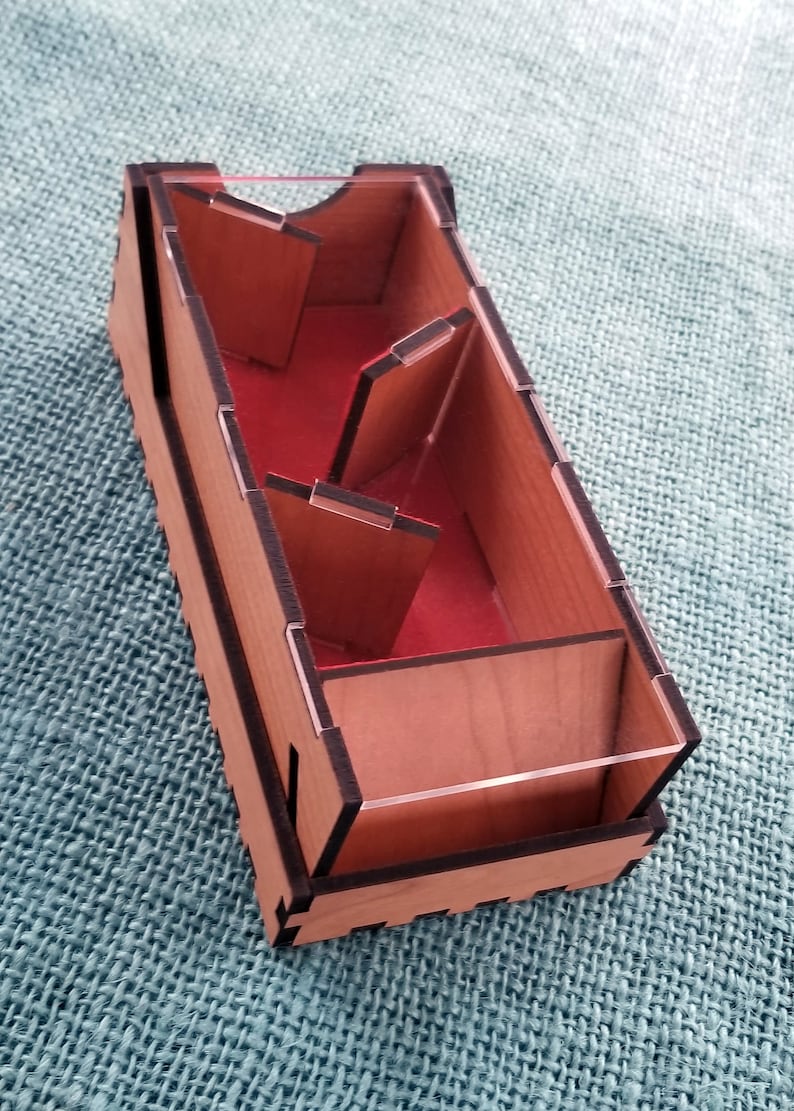 May include: A wooden box with a clear plastic lid and multiple compartments. The box is stained a light brown color and has black edges. The compartments are lined with red felt.