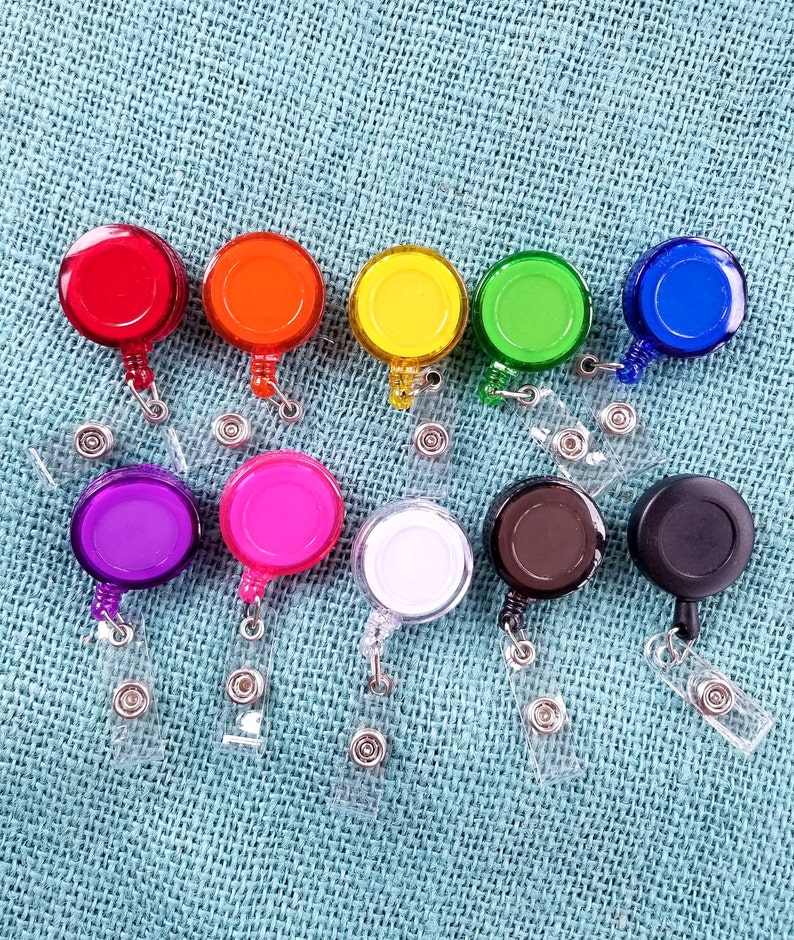 May include: Assortment of 10 colorful retractable badge holders with clear plastic straps. The holders are round and come in red, orange, yellow, green, blue, purple, pink, white, brown, and black.