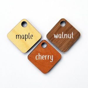 May include: Three wooden squares with rounded corners, each with a hole in the top. The squares are labeled "maple", "walnut", and "cherry".