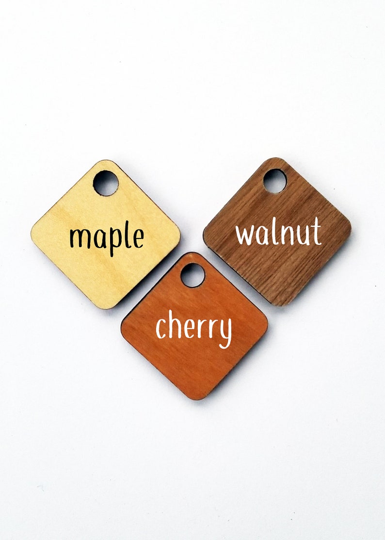 May include: Three wooden squares with rounded corners, each with a hole in the top. The squares are labeled "maple", "walnut", and "cherry".