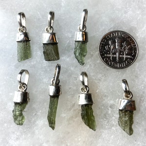 May include: Eight green and silver pendant charms featuring a raw, uncut green gemstone. The charms are approximately the size of a UK ten pence coin.