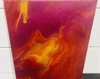 May include: Abstract acrylic painting on canvas. The artwork features a fluid design with a blend of red, orange, and gold hues, set against a deep magenta background. The colours swirl and blend, creating a dynamic and textured effect.