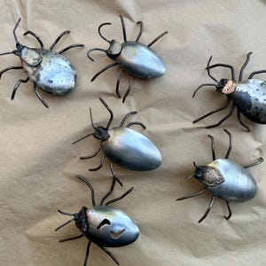 May include: Six metal bug sculptures with a silver finish. Each bug has a different design and is made of recycled metal.