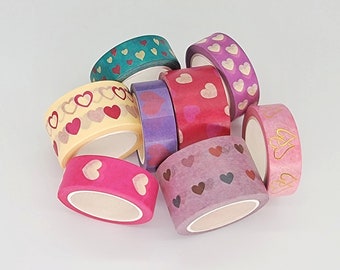 May include: A collection of decorative washi tape rolls in various colors, including pink, purple, teal, and yellow. Each roll features heart patterns in different styles and colors, perfect for crafts and scrapbooking.