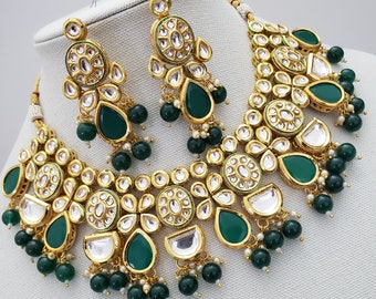 May include: A gold and green Indian bridal necklace set with teardrop-shaped green stones and pearl accents.
