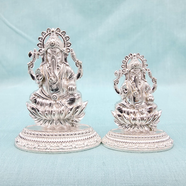 Pu&ograve; includere: Due statue argentate di Ganesha, la divinit&agrave; ind&ugrave;. Sono sedute su basi a forma di fiore di loto con dettagli intricati. La statua pi&ugrave; grande &egrave; alta circa 13 cm, e la pi&ugrave; piccola circa 8 cm.