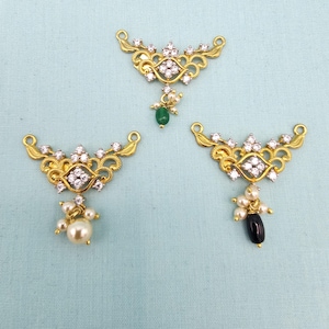 May include: Three gold-toned pendant bases with intricate filigree designs. Each features a central cluster of clear crystals and smaller crystals along the edges. One pendant has a green stone, one has a pearl, and one has a black stone.