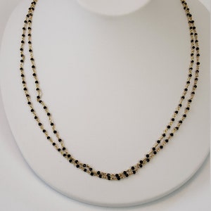 May include: A double strand necklace with black beads and a gold chain.