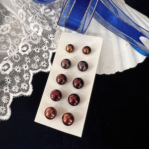 May include: A set of ten brown and black pearl earrings on a white card. The pearls are arranged in two rows of five.