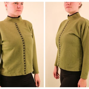 May include: A green mock neck sweater with a black and brown geometric design down the front.
