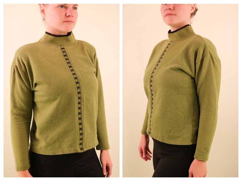 May include: A green mock neck sweater with a black and brown geometric design down the front.