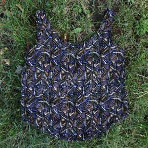 May include: A sleeveless tank top with a geometric pattern in shades of black, gold, purple, and white.