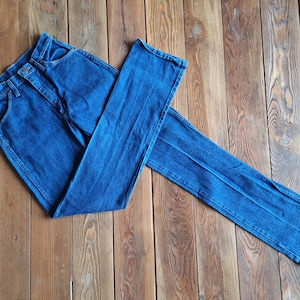May include: A pair of blue denim jeans folded on a wooden surface.