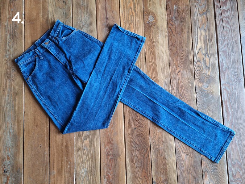 May include: A pair of blue denim jeans folded on a wooden surface.