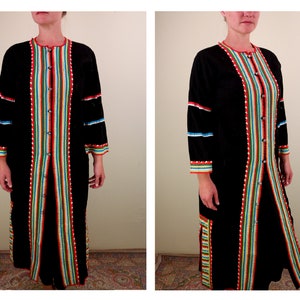 Può includere: Un lungo cardigan nero con strisce colorate sul davanti e sulle maniche. Il cardigan ha una chiusura con bottoni e una silhouette lunga e fluida.