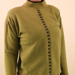 May include: A green mock neck sweater with a black and gold geometric pattern down the front.