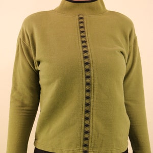 May include: A green mock neck sweater with a black and green geometric pattern down the front.