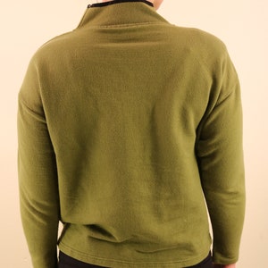 May include: A long-sleeved, olive green sweater with a mock neck and a zipper. The sweater is made of a soft, comfortable fabric.