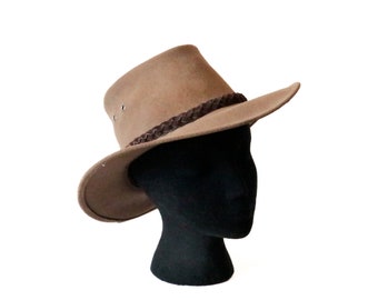 May include: A brown felt cowboy hat with a brown leather band. The hat is sitting on a black mannequin head.