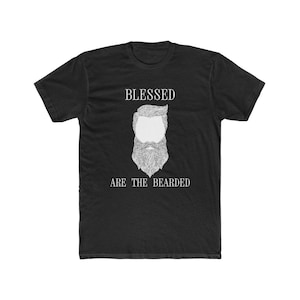 Puede incluir: Camiseta negra con un gráfico blanco de un hombre barbudo y el texto "Blessed are the Bearded".